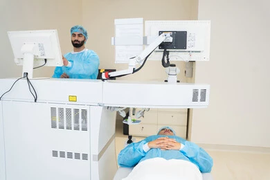 A Saudi Arabian Gulf Arab doctor wearing sterile official attire is reviewing eye radiology images on a computer inside the eye medical center, benefiting from radiographic imaging and modern techniques in the field of ophthalmology, using advanced technology in visual diagnosis and treatment, conducting a thorough examination of the retina and cornea, caring for eye health and improving vision, with an interior background of the medical center.