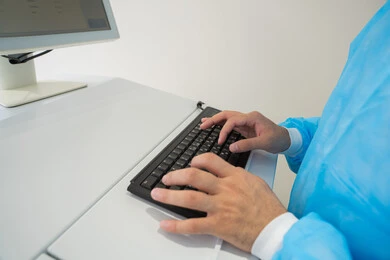 Utilizing radiographic imaging and modern techniques in the field of ophthalmology, employing advanced technology in visual diagnosis and treatment, an Arab Gulf Saudi doctor wearing sterile official attire is reviewing eye radiography images on a computer inside the eye medical center, a thorough examination of the retina and cornea, caring for eye health and improving vision, an interior background of the medical center.