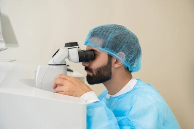 A Saudi Arabian Gulf man wearing sterile attire is examining the eye with an ophthalmoscope, using advanced modern devices, diagnosing and identifying visual problems, assessing the extent of vision and detecting eye diseases, understanding the concept of healthcare services in hospitals and medical centers, and ensuring the accuracy of vision.