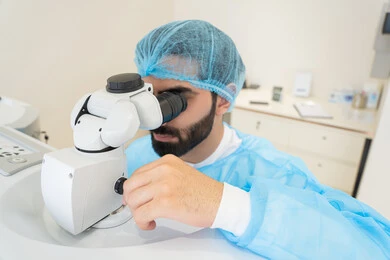The concept of healthcare services in hospitals and medical centers, the use of advanced modern devices, diagnosing and identifying visual problems, an Arab Gulf Saudi man wearing sterile attire examining the eye with an ophthalmoscope, assessing the extent of vision and detecting eye diseases, ensuring the accuracy of vision.