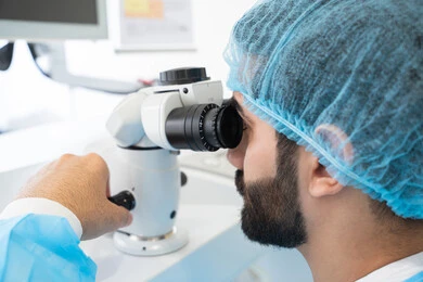 رجل عربي خليجي سعودي يرتدي الزي المعقم يقوم بفحص العين بجهاز المنظار العيني،استخدام الأجهزة الحديثة المتطورة، تشخيص وتحديد المشاكل البصرية، تقييم مدى الرؤية والكشف عن الامراض العينية، مفهوم الخدمات والرعاية الصحية في المشافي والمراكز الطبية ، التأكد من صحة البصر