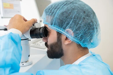 Diagnosis and identification of visual problems, use of advanced modern devices, an Arab Gulf Saudi man wearing sterile attire examining the eye with an ophthalmoscope, assessing the level of vision and detecting eye diseases, the concept of services and healthcare in hospitals and medical centers, ensuring the accuracy of vision.