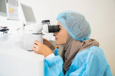 The concept of healthcare services in hospitals and medical centers, the use of advanced modern devices, diagnosing and identifying visual problems, an Arab Gulf Emirati female doctor examining the eye with an ophthalmoscope, assessing the extent of vision and detecting eye diseases, a Saudi woman ensuring the health of her eyesight.