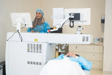 طبيبة عربية خليجية سعودية ترتدي الزي الرسمي المعقم تتابع صور الأشعة العينية على جهاز الحاسوب داخل المركز الطبي للعيون، الاستفادة من التصوير الشعاعي والتقنيات الحديثة في مجال طب العيون، استخدام التكنولوجيا المتطورة في التشخيص والعلاج البصري، فحص دقيق لحالة الشبكية والقرنية، العناية بصحة العين وتحسين الرؤية، خلفية داخلية للمركز الطبي