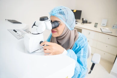 The use of advanced modern devices, diagnosing and identifying visual problems, an Arab Gulf Emirati doctor examining the eye with an ophthalmoscope, assessing the level of vision and detecting eye diseases, the concept of health services and care in hospitals and medical centers, a Saudi woman ensuring the health of vision.
