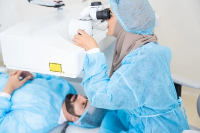 القضاء على مشاكل ضعف النظر وقصر النظر، استعادة وضوح الرؤية بدون الحاجة للنظارات الطبية، عيون صحية ورؤية أكثر دقة، رجل عربي خليجي سعودي  يرتدي الزي الرسمي المعقم ، طبيبه سعوديه تكشف لإجراء عملية الليزك داخل المراكز الطبية، عملية تصحيح الإبصار بالليزر، الاهتمام بالعناية بالعين وتحسين البصر