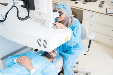 Laser vision correction procedure, eliminating problems of poor vision and nearsightedness, restoring clear vision without the need for glasses, healthy eyes and more accurate vision, a Saudi Arabian Gulf man wearing sterile official attire, a Saudi female doctor revealing to perform LASIK surgery inside medical centers, focusing on eye care and improving vision.