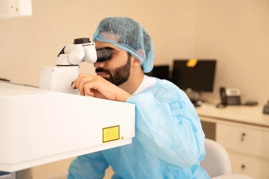 The use of advanced modern devices, diagnosing and identifying visual problems, an Arab Gulf Saudi man wearing sterile attire examining the eye with an ophthalmoscope, assessing the extent of vision and detecting eye diseases, the concept of services and healthcare in hospitals and medical centers, ensuring the accuracy of vision.