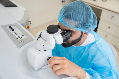 The use of advanced modern devices, diagnosing and identifying visual problems, an Arab Gulf Saudi man wearing sterile attire examining the eye with an ophthalmoscope, assessing the extent of vision and detecting eye diseases, the concept of services and healthcare in hospitals and medical centers, ensuring the accuracy of vision.