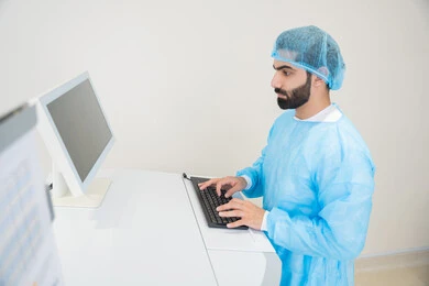 Utilizing radiographic imaging and modern techniques in the field of ophthalmology, employing advanced technology in visual diagnosis and treatment, an Arab Gulf Saudi doctor wearing sterile official attire is reviewing eye radiography images on a computer inside the eye medical center, a thorough examination of the retina and cornea, caring for eye health and improving vision, an interior background of the medical center.
