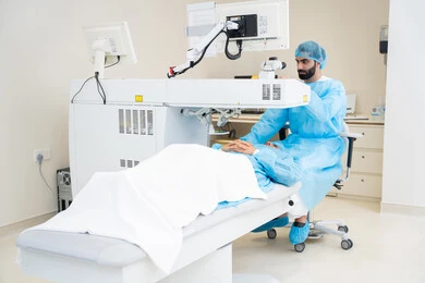 Eliminating problems of poor vision and nearsightedness, restoring clear vision without the need for glasses, healthy eyes and more accurate vision, a Saudi Gulf Arab boy wearing sterile official attire sitting on the clinic chair, a Saudi doctor revealing to perform LASIK surgery inside medical centers, laser vision correction surgery, focusing on eye care and improving vision.