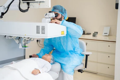 Attention to eye care and vision improvement, laser vision correction procedure, eliminating problems of poor vision and nearsightedness, restoring clear vision without the need for prescription glasses, healthy eyes and more accurate vision, a Saudi Arabian Gulf boy wearing sterile official attire sitting on the clinic chair, a Saudi doctor revealing to perform LASIK surgery inside medical centers.