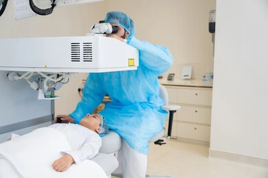 Laser vision correction surgery, eliminating problems of poor vision and nearsightedness, restoring clear vision without the need for glasses, healthy eyes and more accurate vision, a Saudi Arabian Gulf boy wearing sterile official attire sitting in the clinic chair, a Saudi doctor revealing to perform LASIK surgery inside medical centers, focusing on eye care and improving vision.