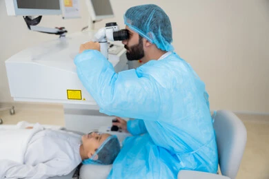 Attention to eye care and vision improvement, laser vision correction procedure, eliminating problems of poor vision and nearsightedness, restoring clear vision without the need for prescription glasses, healthy eyes and more accurate vision, a Saudi Arabian Gulf boy wearing sterile official attire sitting on the clinic chair, a Saudi doctor revealing to perform LASIK surgery inside medical centers.