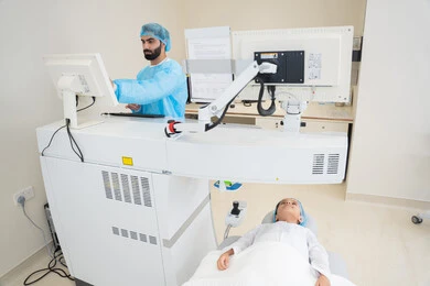 استخدام التكنولوجيا المتطورة في التشخيص والعلاج البصري، الاستفادة من التصوير الشعاعي والتقنيات الحديثة في مجال طب العيون، طبيب عربي خليجي سعودي يرتدي الزي الرسمي المعقم يتابع صور الأشعة العينية على جهاز الحاسوب داخل المركز الطبي للعيون، فحص دقيق لحالة الشبكية والقرنية، العناية بصحة العين وتحسين الرؤية، خلفية داخلية للمركز الطبي