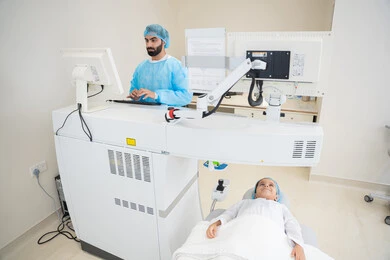 Utilizing radiographic imaging and modern techniques in the field of ophthalmology, employing advanced technology in visual diagnosis and treatment, an Arab Gulf Saudi doctor wearing sterile official attire is reviewing eye radiography images on a computer inside the eye medical center, a thorough examination of the retina and cornea, caring for eye health and improving vision, an interior background of the medical center.