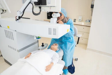 Attention to eye care and vision improvement, laser vision correction procedure, eliminating problems of poor vision and nearsightedness, restoring clear vision without the need for prescription glasses, healthy eyes and more accurate vision, a Saudi Arabian Gulf boy wearing sterile official attire, a Saudi female doctor reveals to perform LASIK surgery inside medical centers.