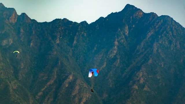 A beautiful image of a sports glider flying in the sky, riding the glider, enjoying the landscapes, a sightseeing trip in the air, tourist spots in the Kingdom of Saudi Arabia, the beauty of the natural scenery, mountainous highlands.