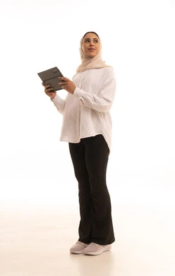 Looking at something, browsing websites and social media, the concept of remote project completion, integrating technology into daily and professional life, a portrait of a young Arab Gulf Saudi woman wearing a hijab in casual attire using a tablet, full-body, white background.