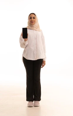 عرض تطبيقات الهاتف المحمول، التسويق الالكتروني باستخدام التقنية والتكنولوجيا، بورتريه لشابة عربيه خليجية سعودية محجبة ترتدي الزي الكاجول تحمل بيدها جوال بشاشة سوداء فارغة، النظرالى الكاميرا بتعابير السرور، خلفية بيضاء