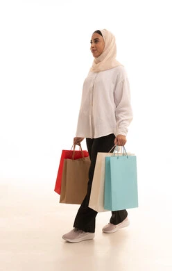 The beginning of the discount and promotion season in the markets, gestures of happiness and the feeling of the joy of shopping, buying gifts and necessities, the positive effect of shopping on women's psychology, a side portrait of a young Arab Gulf Saudi woman wearing casual attire, holding colorful shopping bags in her hand, full-body shot, white background. The beginning of the discount and promotion season in the markets, gestures of happiness and the feeling of the joy of shopping, buying gifts and necessities, the positive effect of shopping on women's psychology, a side portrait of a young Arab Gulf Saudi woman wearing casual attire, holding colorful shopping bags in her hand, full-body shot, white background.