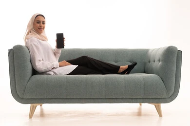 A blank black screen displayed on a mobile phone, using electronic programs and applications, a portrait of a young Arab Gulf Saudi woman wearing a hijab in casual attire sitting on a sofa using a mobile phone, white background.