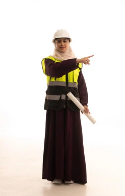 التحقق من تنفيذ المشروع الإنشائي, مهنة ووظيفة نسائية، مفهوم الهندسة والإنشاء المعماري، بورتريه لمهندسة عربية خليجية سعودية محجبة ترتدي العباءة والسترة و خوذة الحماية تمسك بيدها المخطط الهندسي،الاشارة الى شيء ما،  صورة الجسم بالكامل، خلفية بيضاء