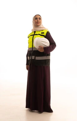 تقدم وتطور السعودية على يد أبناء الوطن،  مهن ووظائف نسائية، مفهوم الهندسة وأعمال البناء، بورتريه لمهندسة عربية خليجية سعودية محجبة ترتدي عباءة مع السترة تمسك بيدها خوذة الحماية، العمل  في القطاع الهندسي السعودي ,الجسم بالطول الكامل، خلفية بيضاء