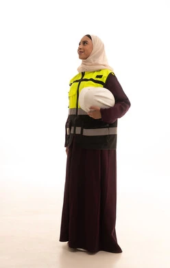 مهن ووظائف نسائية، مفهوم الهندسة وأعمال البناء، تقدم وتطور السعودية على يد أبناء الوطن، بورتريه لمهندسة عربية خليجية سعودية محجبة ترتدي عباءة مع السترة تمسك بيدها خوذة الحماية، العمل  في القطاع الهندسي السعودي ,الجسم بالطول الكامل، خلفية بيضاء