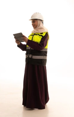 Study the fundamentals of the project through tablet applications, professions and jobs for Saudi women, adopting modern technologies and technology in engineering, a portrait of a Saudi Gulf Arab engineer wearing a jacket and safety helmet monitoring the factory operations using a tablet, full-body, white background.