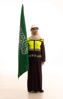 The concept of love for the homeland and belonging to it, Saudi Flag Day on March 11, the anniversary of the day we began in 1727 AD, the celebration of the establishment of the first Saudi state on February 22, a portrait of an Arab Gulf Saudi engineer wearing a helmet and protective vest holding the flag and emblem of the Kingdom, looking with gestures of pride and honor, full-body, white background.