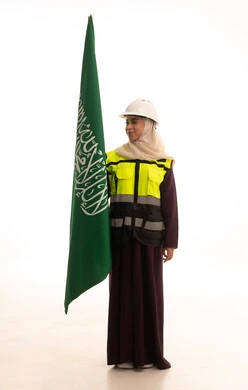 يوم العلم السعودي11 مارس، ذكرى يوم بدينا 1727 م، مفهوم حب الوطن و الانتماء اليه، الاحتفال بتأسيس الدولة السعودية الأولى 22 فبراير، بورتريه لمهندسة عربية خليجية سعودية ترتدي خوذة وسترة الحماية تمسك راية وشعار المملكة تنظر بايماءات الاعتزاز و الفخر, الجسم بالطول الكامل, خلفية بيضاء