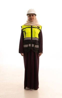 Looking at the camera with expressions of happiness and joy, women's jobs and professions, the concept of engineering project management, standing with gestures of confidence, a portrait of a Gulf Arab Saudi female engineer wearing a helmet and safety vest standing upright, full-body image, white background.