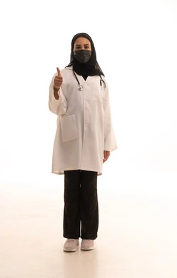 مفهوم الإعجاب والرضا، علامة الجودة و الامتياز, تقديم الرعاية الطبية للمرضى، بورتريه لطبيبة عربية خليجية سعودية ترتدي المعطف الطبي الأبيض وكمامة الوقاية تشير بإصبع الابهام الى الاعلى بإيماءات الموافقة، الالتزام بالاحترازات الوقائيه ضد كوفيد 19، الجسم بالطول الكامل، خلفية بيضاء