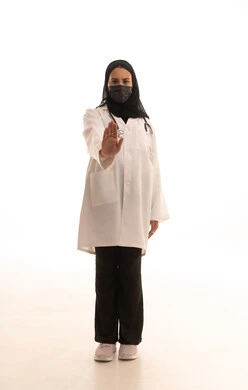 الالتزام بقواعد السلامة الصحية ضد كوفيد-19، تعابير الحزم والجدية, مفهوم الرفض والامتناع والانزعاج, طلب التوقف وعدم الاقتراب, ورتريه لطبيبة عربية خليجية سعودية محجبة ترتدي المعطف الطبي و الكمامة تمد يديها نحو الأمام مع رفع الكف بإيماءات النهي عن فعل امر ما, صورة الجسم بالطول الكامل، خلفية بيضاء