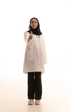 تقييم ممتاز للخدمات الطبية، بورتريه لطبيبة عربية خليجية سعودية محجبة ترتدي المعطف الطبي ترفع اصبع الإبهام للاعلى، مفهوم الطب والرعاية الصحية، إيماءات وجه سعيدة ويدين تدل على القبول والموافقة، الجسم بالطول الكامل، خلفية بيضاء