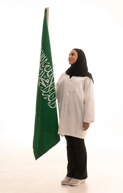 مفهوم حب الوطن و الانتماء الية،  ذكرى توحيد المملكة العربية السعودية، الاحتفال باليوم الوطني السعودي بفخر وعزة ، العلم السعودي راية التوحيد والاسلام , بورتريه لطبيبة عربية خليجية سعودية محجبة ترتدي المعطف الطبي تقف باستقامة تنظر بايماءات الفخر، الجسم بالطول الكامل، خلفية بيضاء