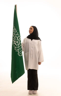 الاحتفال باليوم الوطني السعودي بفخر وعزة ، العلم السعودي راية التوحيد والاسلام , بورتريه لطبيبة عربية خليجية سعودية محجبة ترتدي المعطف الطبي تقف باستقامة تنظر بايماءات الفخر، ذكرى توحيد المملكة العربية السعودية، الجسم بالطول الكامل، خلفية بيضاء
