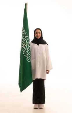 العلم السعودي راية التوحيد والاسلام , الاحتفال باليوم الوطني السعودي بفخر وعزة , بورتريه لطبيبة عربية خليجية سعودية محجبة ترتدي المعطف الطبي تقف باستقامة تنظر بايماءات الفخر، ذكرى توحيد المملكة العربية السعودية، الجسم بالطول الكامل، خلفية بيضاء