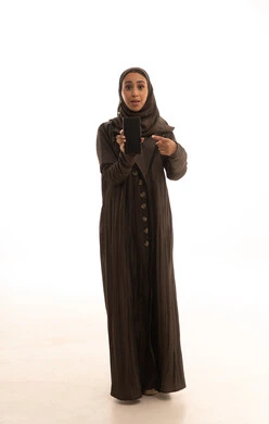 النظر الى الكاميرا بايماءات الذهول والدهشة، الاستغراب والانبهار والحماس، عرض شاشة سوداء فارغة عبر الجوال، استخدام جهاز تقني حديث ومتطور، بورتريه لامرأة عربية خليجية سعودية محجبة تحمل بيدها الهاتف المحمول، الجسم بالطول الكامل، خلفية بيضاء