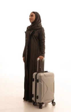 The concept of tourism and travel, a side portrait of a smiling Saudi Gulf Arab woman holding a suitcase, preparing and packing luggage for a tourist trip, with facial expressions indicating excitement for the journey, full body, white background.