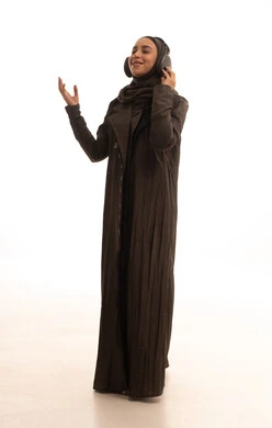 إستخدام تقنيات الهيدفون،  قضاء اوقات ممتعة ومسلية، مفهوم الإصغاء والإستماع، بورتريه لامرأة عربية خليجية سعودية محجبة ترتدي العباءة تضع سماعات الرأس الصوتية تستمع إلى الموسيقى،ايماءات السعادة والسرور، صورة لكامل الجسم، خلفية بيضاء