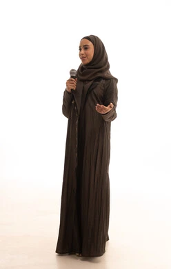 Artistic talents in the world of music, musical theater, practicing singing as a hobby for fun and entertainment, presenting theatrical performances, a portrait of an Arab Gulf Saudi woman wearing an abaya and hijab holding a microphone in her hands, full body length, white background.