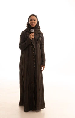 Practicing the hobby of singing for fun and entertainment, musical theater art, artistic talents in the world of music, presenting theatrical performances, a portrait of an Arab Gulf Saudi woman wearing an abaya and hijab holding a microphone in her hands, full body length, white background.