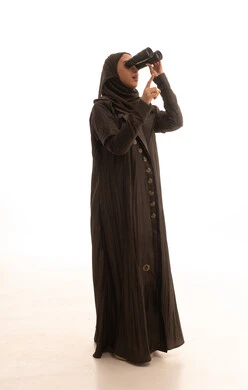 Future planning for goals and ambitions, pointing to something, thinking and looking forward to the future, seeing distant things, love for exploration and adventure, a portrait of a young Arab Gulf Saudi woman wearing an abaya and hijab holding binoculars looking at something, full-body, white background.