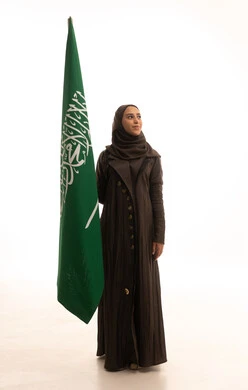 الاحتفال بتأسيس الدولة السعودية الأولى 22 فبراير، مفهوم حب الوطن و الانتماء اليه، يوم العلم السعودي11 مارس، ذكرى يوم بدينا 1727 م، بورتريه لإمرأة عربية خليجية سعودية ترتدي العباءة و الحجاب تمسك راية وشعار المملكة تنظر بايماءات الاعتزاز و الفخر, الجسم بالطول الكامل, خلفية بيضاء