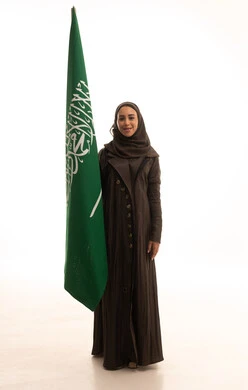 يوم العلم السعودي11 مارس، مفهوم حب الوطن و الانتماء اليه، الاحتفال بتأسيس الدولة السعودية الأولى 22 فبراير، ذكرى يوم بدينا 1727 م، بورتريه لإمرأة عربية خليجية سعودية ترتدي العباءة و الحجاب تمسك راية وشعار المملكة تنظر بايماءات الاعتزاز و الفخر, الجسم بالطول الكامل, خلفية بيضاء