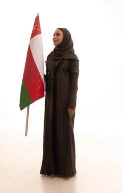 حب الوطن كجزء من الهوية والانتماء، ثقافات ورموز وطنية، إحياء ذكرى تأسيس الدولة 1775 م, بورترية لإمراة عربية عمانية خليجية محجبة ترتدي العباءة تمسك العلم الوطني للبلاد تحتفل بذكرى اليوم الوطني العماني 18 نوفمبر، الجسم بالطول الكامل، خلفية بيضاء