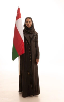 حب الوطن والانتماء إليه، إحياء ذكرى تأسيس الدولة 1775 م، ثقافات ورموز وطنية, بورترية لإمراة عربية عمانية خليجية محجبة ترتدي العباءة تمسك العلم الوطني للبلاد تحتفل بذكرى اليوم الوطني العماني 18 نوفمبر، الجسم بالطول الكامل، خلفية بيضاء