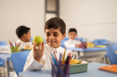Enjoying healthy food during school break, back-to-school season, a group of Arab Gulf Saudi students sitting in their seats with lunch boxes in front of them, meals rich in essential nutrients for building the body. Enjoying healthy food during school break, back-to-school season, a group of Arab Gulf Saudi students sitting in their seats with lunch boxes in front of them, meals rich in essential nutrients for building the body.